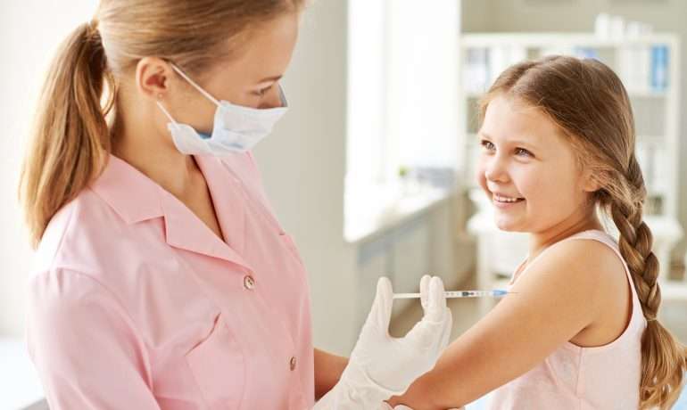 A young girl receiving a flu shot from a doctor during COVID-19.