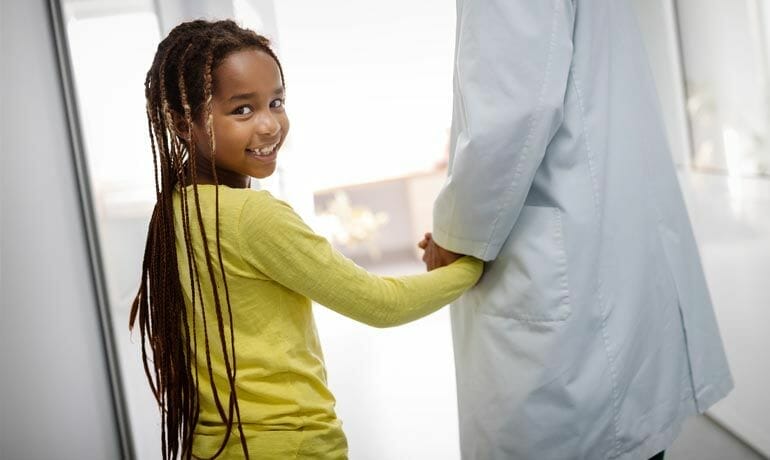 A young girl is shaking hands with a doctor at Pediatrics of Sugar Land.