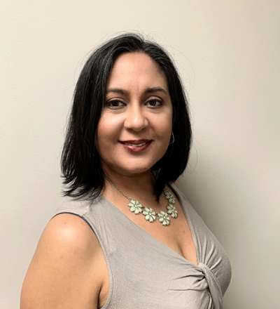 A woman wearing a gray top and a necklace.