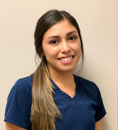 A smiling young woman in a scrub shirt.