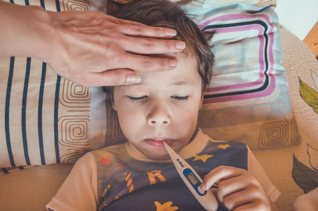 A well child in Sugar Land is lying down with a thermometer in his hand during a check-up.