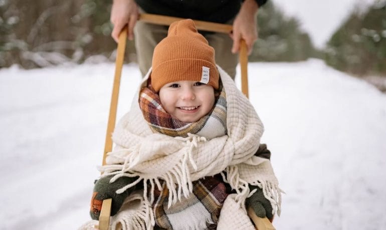 A child is pulling a sled in the snow.
