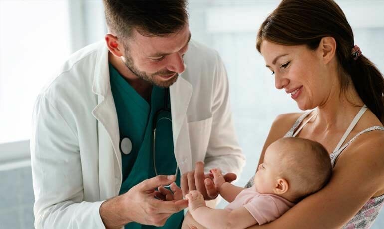 A doctor examines a baby while the mother learns tips for promoting healthy eating in children.
