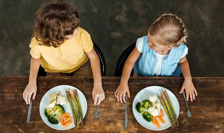 Two children learn about healthy eating at a table.