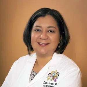 A woman pediatrician in a white lab coat posing for a photo.