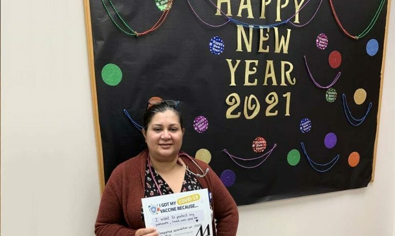 A woman standing in front of a bulletin board with a happy new year sign.