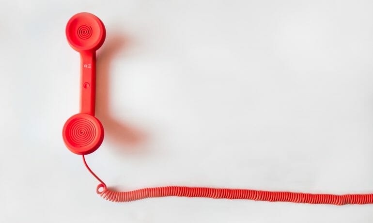A red telephone on a white surface resembling a pediatrician's office phone.