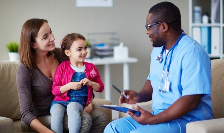 A doctor is talking to a young girl in a waiting room.