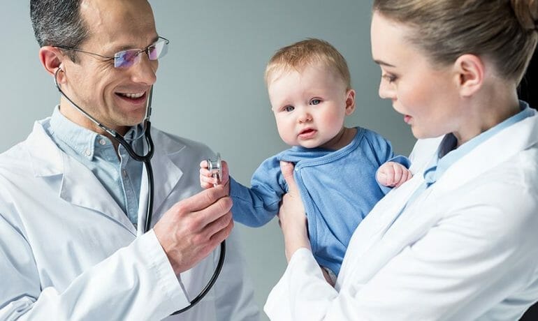 A baby is examined by a doctor with a stethoscope to determine when to get a pediatrician.