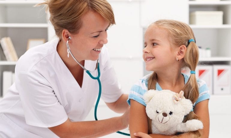 A young girl holding a teddy bear and a stethoscope.