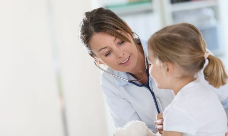 A young girl is being examined by a doctor with a stethoscope.